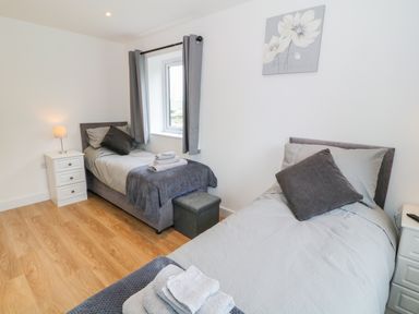 A bedroom with two single beds bedside tables with lamps and folded towels on the beds at Llwyd Coed Canol in Llanllyfni near Penygroes