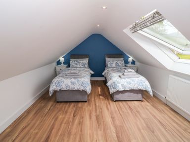 A bedroom with two single beds and bedside tables under a sloped ceiling with a skylight window at Llwyd Coed Canol in Llanllyfni near Penygroes