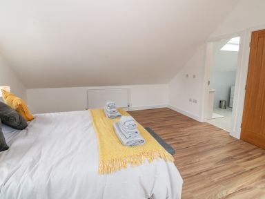 A bedroom with a bed made with white and yellow bedding and folded towels on top at Llwyd Coed Canol in Llanllyfni near Penygroes