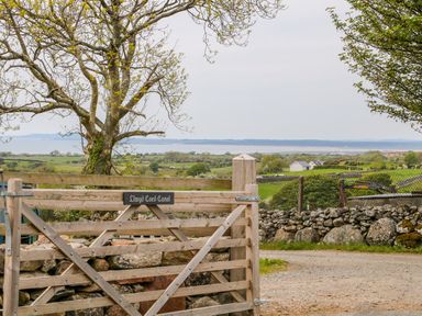 A wooden gate with a stone wall and trees overlooking a rural landscape at Llwyd Coed Canol in Llanllyfni near Penygroes