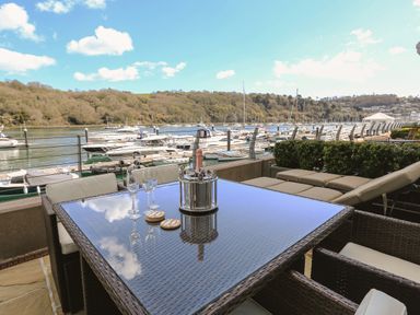 Outdoor patio with a table set with wine glasses and a champagne bucket overlooking boats at Quayside Dart Marina in Dartmouth
