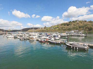 Boats docked at a marina with hills and houses in the background at Quayside Dart Marina in Dartmouth