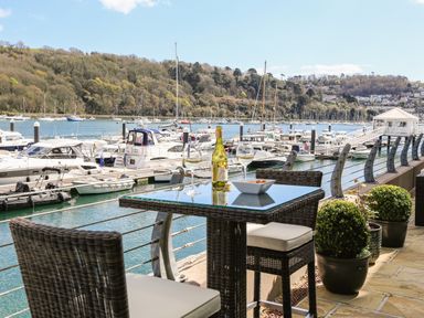 An outdoor patio with a table and chairs overlooking a marina with boats at Quayside Dart Marina in Dartmouth