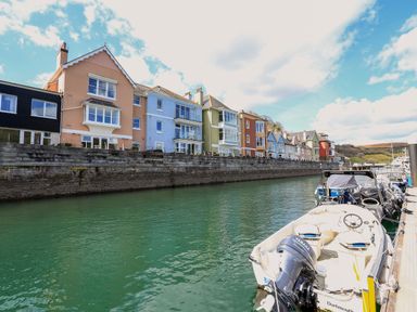 A row of colorful houses along a waterfront with boats docked at a marina at Quayside Dart Marina in Dartmouth