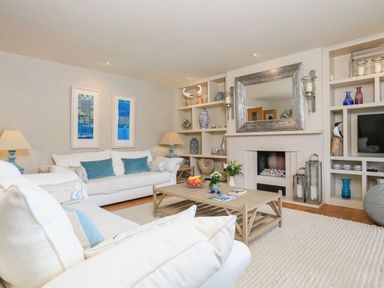 A living room with white sofas a wooden coffee table a fireplace and built-in shelves at Quayside Dart Marina Dartmouth