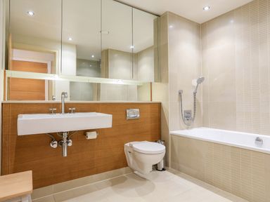 A bathroom with a wall-mounted sink toilet and bathtub with shower at Quayside Dart Marina in Dartmouth