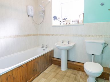 A bathroom with a bathtub shower sink and toilet at Dyfi Cottage in Dolgellau