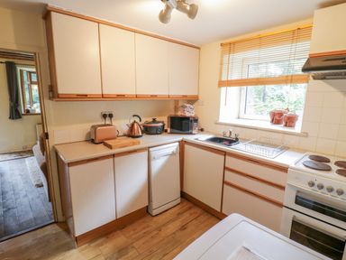 A kitchen with upper and lower cabinets toaster kettle microwave dishwasher sink and stove at Dyfi Cottage in Dolgellau
