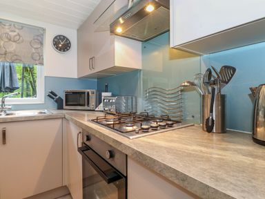 A kitchen with a gas stove oven microwave sink and utensils on the countertop at 40 Skiptory Howe in Troutbeck Bridge