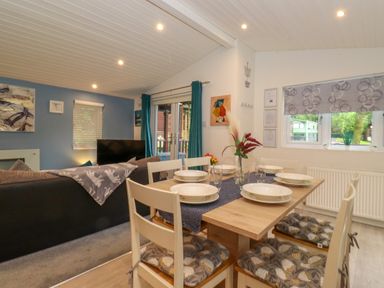 A dining table set with plates and glasses next to a living room with a sofa and television at 40 Skiptory Howe in Troutbeck Bridge