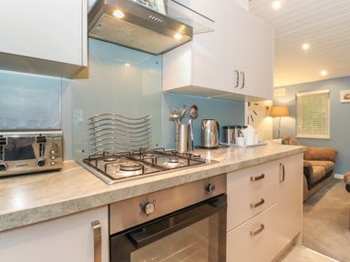 A kitchen with a gas stove oven toaster kettle and utensils near a living area at 40 Skiptory Howe in Troutbeck Bridge