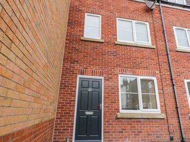 Front view of a brick house with a black door number 25 and three white framed windows at Valiant House in Scarborough