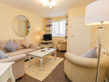 A living room with sofas a coffee table a television and a window at Valiant House in Scarborough