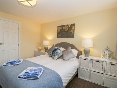 A bedroom with a bed with pillows and folded towels on a blanket and bedside tables with lamps and baskets at Valiant House Scarborough