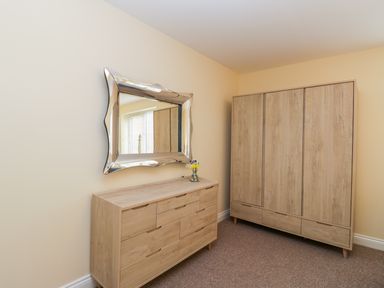 A room with a wooden dresser and a matching wardrobe a decorative mirror and a small vase with flowers on the dresser at Valiant House Scarborough