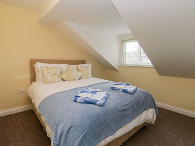 A bedroom with a double bed a window with blinds and slanted walls at Valiant House in Scarborough