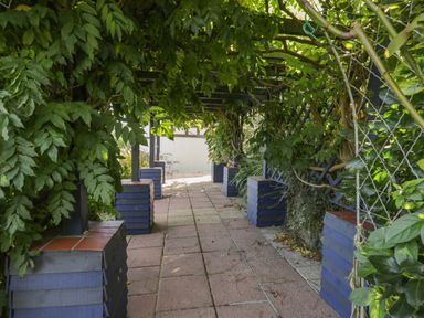 A garden walkway with tiled floor and trellis covered with green foliage at Tudor House in Symonds Yat