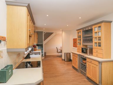 A kitchen with wooden cabinets a microwave and an induction stove at Tudor House in Symonds Yat