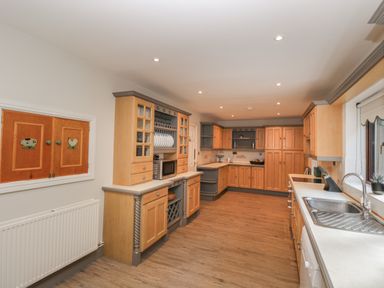 A kitchen with wooden cabinets a sink microwave and a window at Tudor House in Symonds Yat