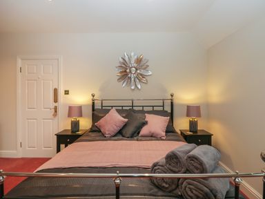 A bedroom with a double bed pillows bedside tables with lamps and rolled towels at Tudor House in Symonds Yat