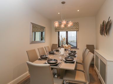 A dining room with a table set for eight people chairs a window and wall decorations at Tudor House in Symonds Yat