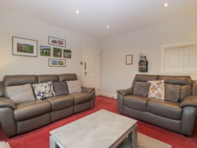 A living room with two brown leather sofas cushions a grey coffee table and framed pictures on the wall at Tudor House in Symonds Yat
