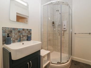 A bathroom with a sink vanity unit mirror and a corner shower enclosure at Tudor House in Symonds Yat