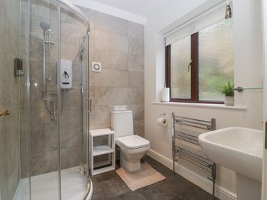 A bathroom with a corner shower enclosure toilet sink and a window at Tudor House in Symonds Yat