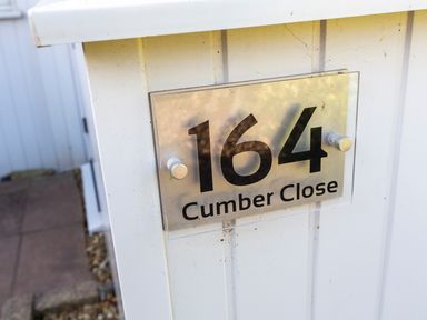A house number sign displaying 164 Cumber Close on a white fence at 164 Cumber Close in Malborough