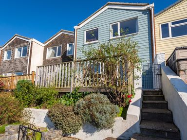 A row of houses with wooden siding and small front gardens with stairs and railings at 164 Cumber Close in Malborough