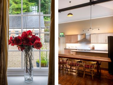 A vase with red flowers on a windowsill and a kitchen with wooden chairs and cabinets at The Old School in Gortin
