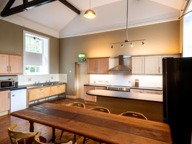 A kitchen with wooden table and chairs stove and refrigerator at The Old School in Gortin