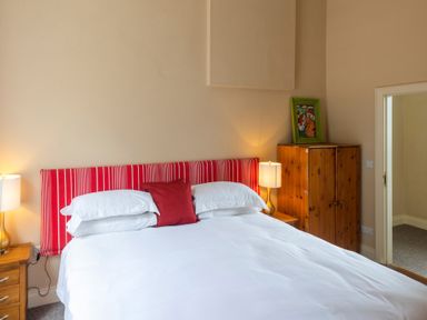 A bedroom with a bed having a red striped headboard and white bedding with side tables and lamps at The Old School in Gortin