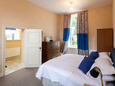 A bedroom with a bed and blue pillows next to a window with blue and patterned curtains at The Old School in Gortin