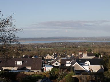 A hillside view of rooftops with a river and fields in the background at Isallt in Rhostryfan near Bontnewydd Gwynedd