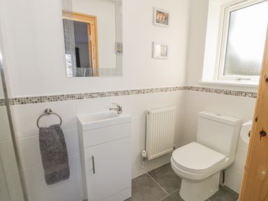 A bathroom with a toilet sink under a mirror with a towel on a ring at Isallt in Rhostryfan near Bontnewydd Gwynedd