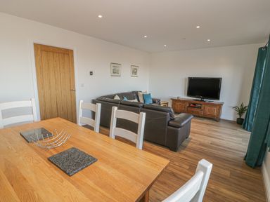 A living room with a dining table and chairs sofa television and wooden cabinet at Isallt in Rhostryfan near Bontnewydd Gwynedd