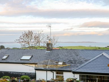 Rooftop of a house with skylights and an outdoor laundry drying rack near green fields and a body of water at Woodleigh Cottage in Ballycastle