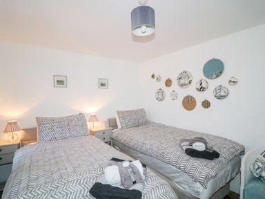 A bedroom with two single beds with striped bedding and bedside tables with lamps at Woodleigh Cottage in Ballycastle