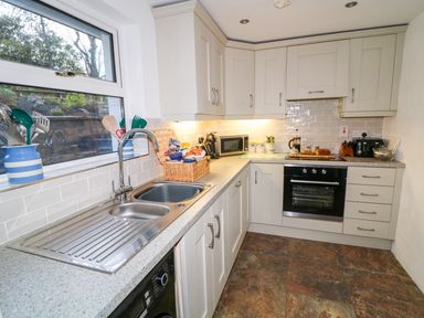 A kitchen with a double sink microwave oven and countertop appliances at Woodleigh Cottage in Ballycastle