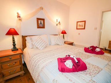 A bedroom with a double bed with towels and lamps on wooden bedside tables at Woodleigh Cottage in Ballycastle