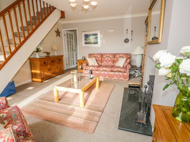 A living room with patterned sofas a coffee table a wooden sideboard and a fireplace at Kirkstone Cottage Outgate near Hawkshead