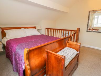 A bedroom with a wooden bed covered with a purple quilt and a wooden bench at Kirkstone Cottage in Outgate near Hawkshead