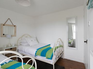A bedroom with two single beds with blue and green blankets a small nightstand with cups and a lamp a wall mirror and a full-length wall mirror at Fenders Brewers Quay Harbour