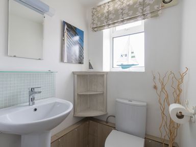 A bathroom with a sink toilet corner shelf and a window with a boat decoration at Fenders in Brewers Quay Harbour