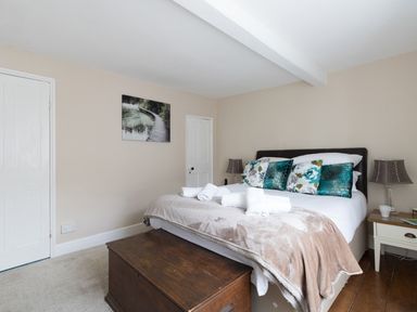 A bedroom with a bed with pillows and folded towels a wooden chest and two bedside tables with lamps at Fenders Brewers Quay Harbour