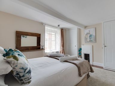 A bedroom with a bed made with white linens and rolled towels near a window with sheer curtains at Fenders Brewers Quay Harbour