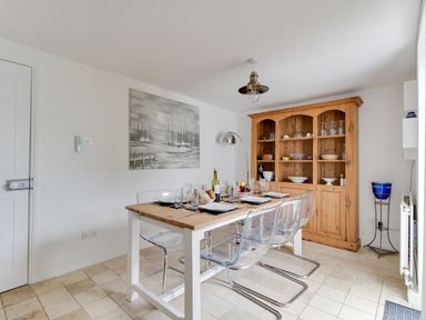 A dining area with a wooden table set with plates and glasses and transparent chairs at Fenders in Brewers Quay Harbour