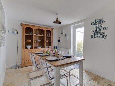 A dining room with a wooden table set for six with clear chairs and a wooden cabinet at Fenders Brewers Quay Harbour