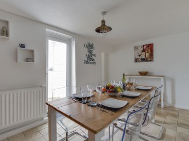 A dining room with a wooden table set with plates glasses and cutlery and transparent chairs at Fenders in Brewers Quay Harbour
